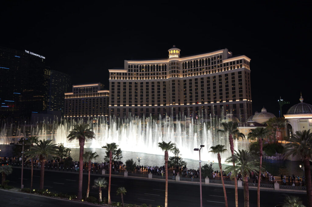 Bellagio fountains lit up at night with hotel in background