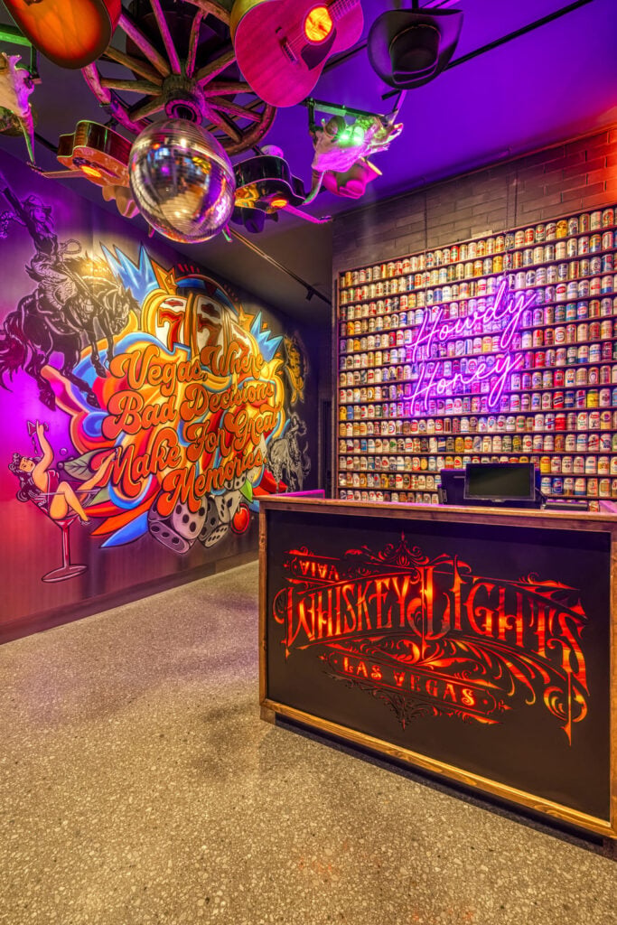 Colorful entrance with neon signs wall of beer cans disco ball and Vegas Where Bad Decisions Make Great Memories mural