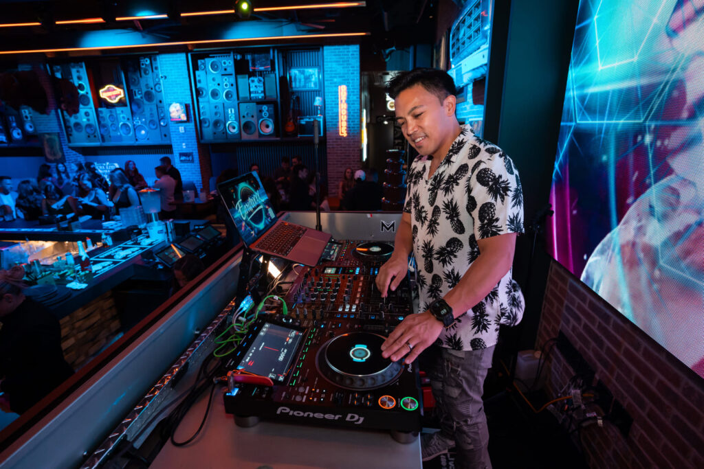DJ performing at Bottled Blonde with a Pioneer DJ controller and crowd in background