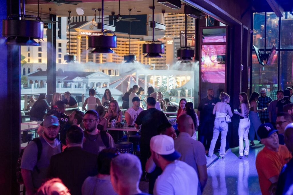 Guests enjoy a busy Las Vegas rooftop bar with views of Caesars Palace and city lights
