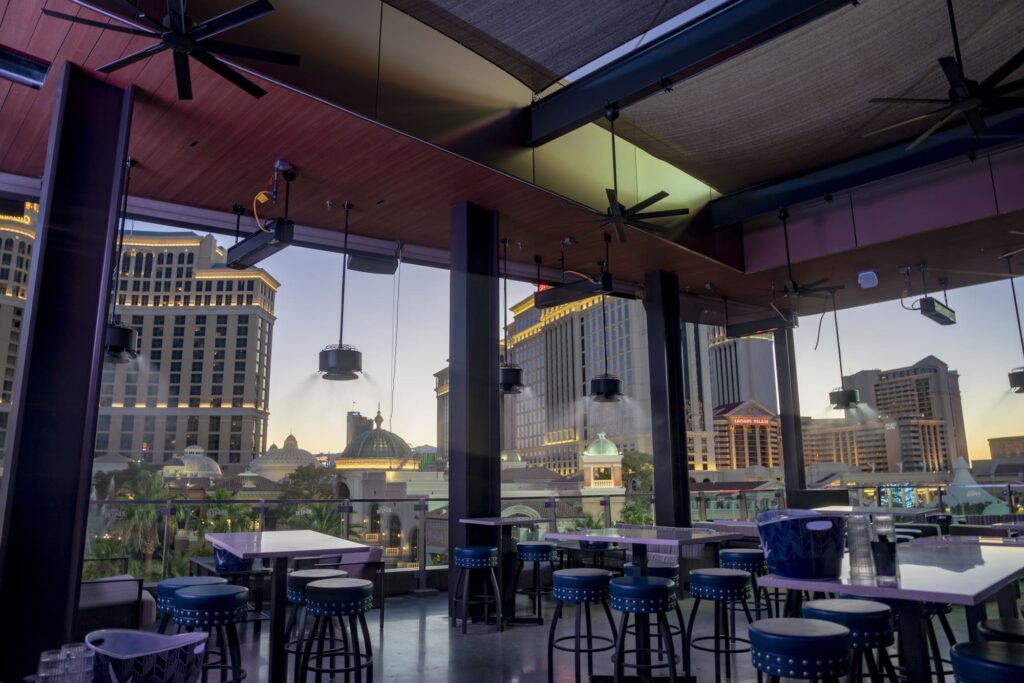 Modern rooftop seating area with views of Caesars Palace and Las Vegas architecture at sunset