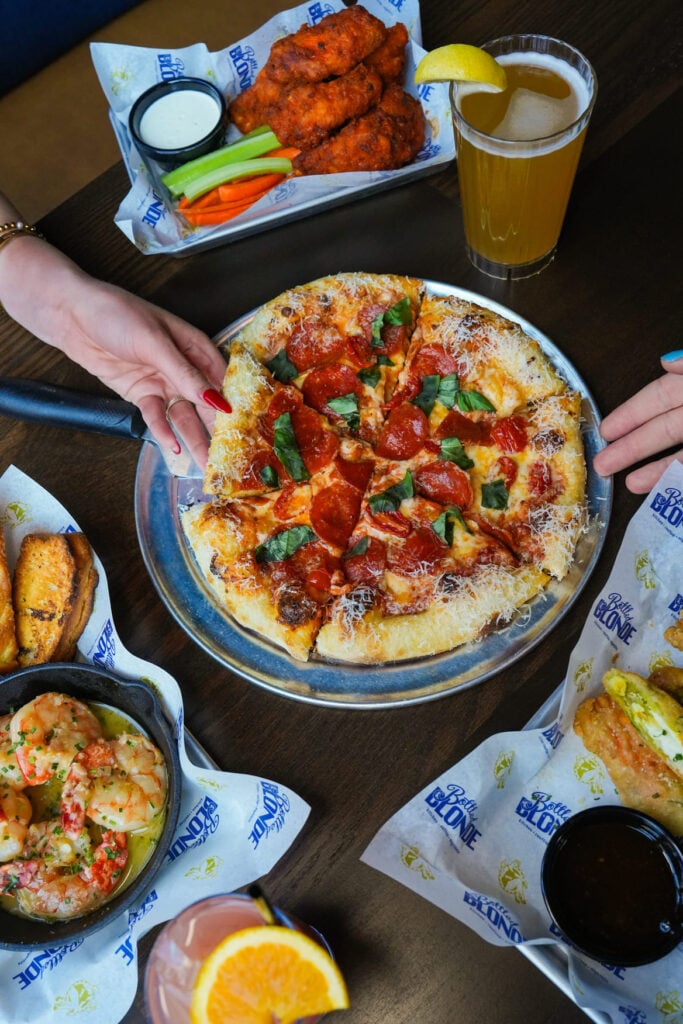 Pizza with pepperoni and basil served with buffalo wings shrimp and drinks