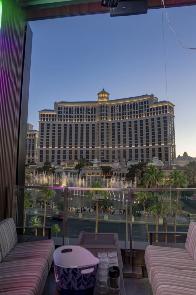Rooftop view of the Bellagio hotel and fountains at dusk with cozy lounge seating in the foreground