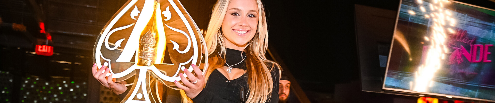 girl holding an illuminated sign with a champagne bottle inside.