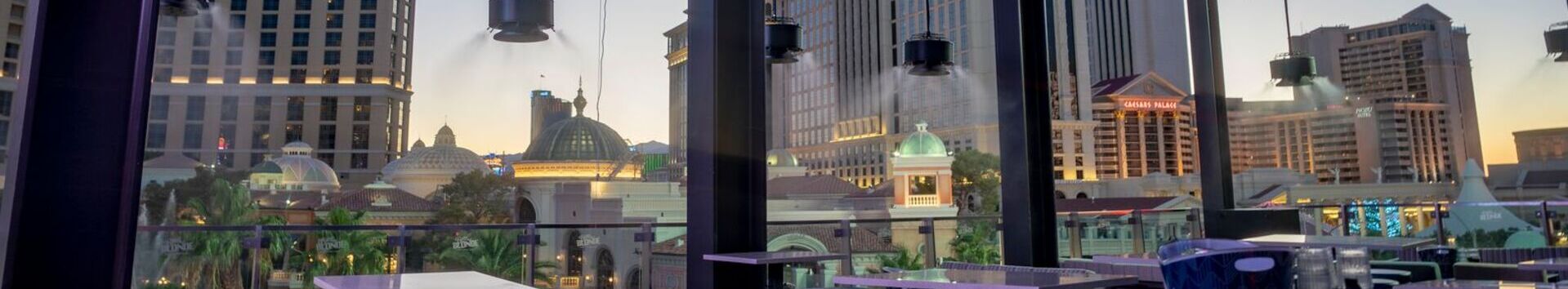 Modern rooftop seating area with views of Caesars Palace and Las Vegas architecture at sunset.