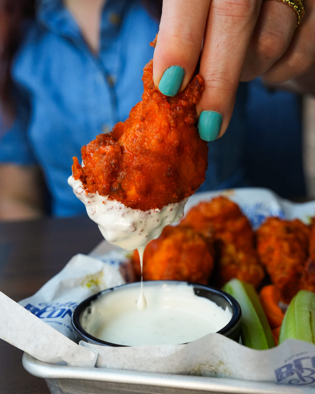 Hand dipping buffalo chicken wing into ranch dressing