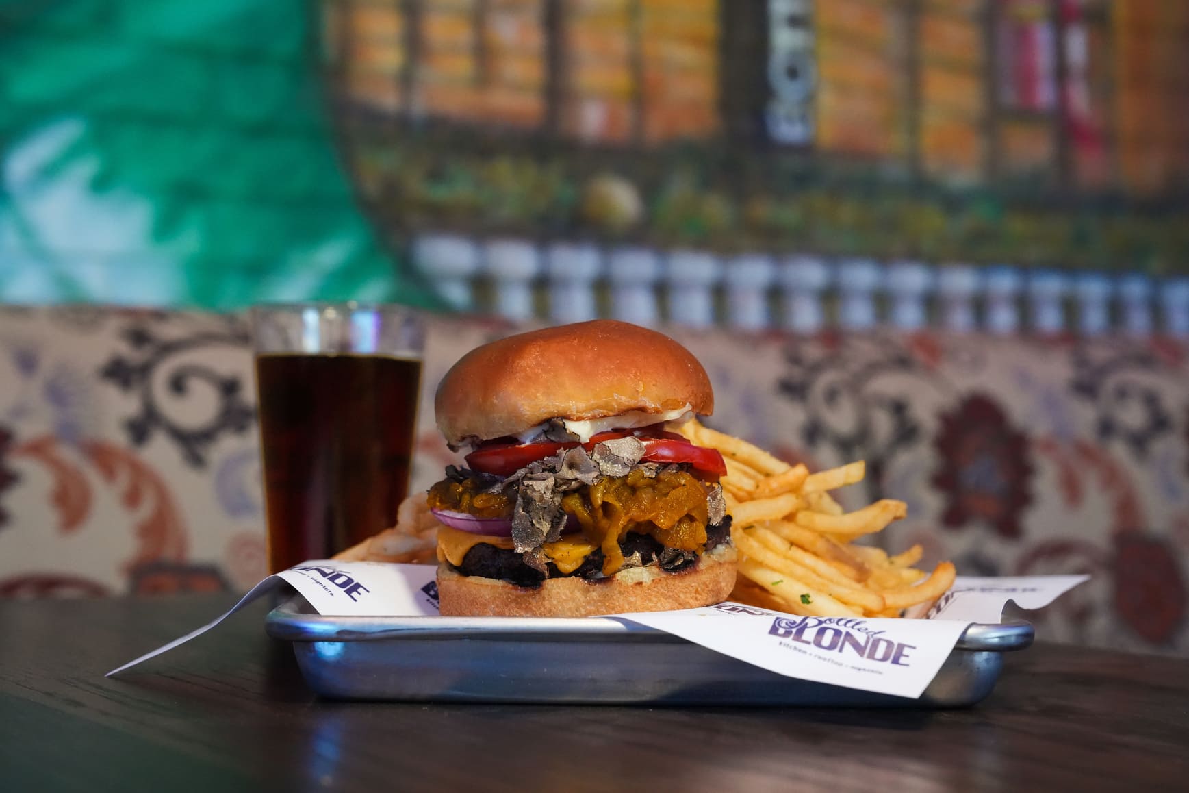 Burger with cheddar, tomato, and mushrooms served with fries and dark soda