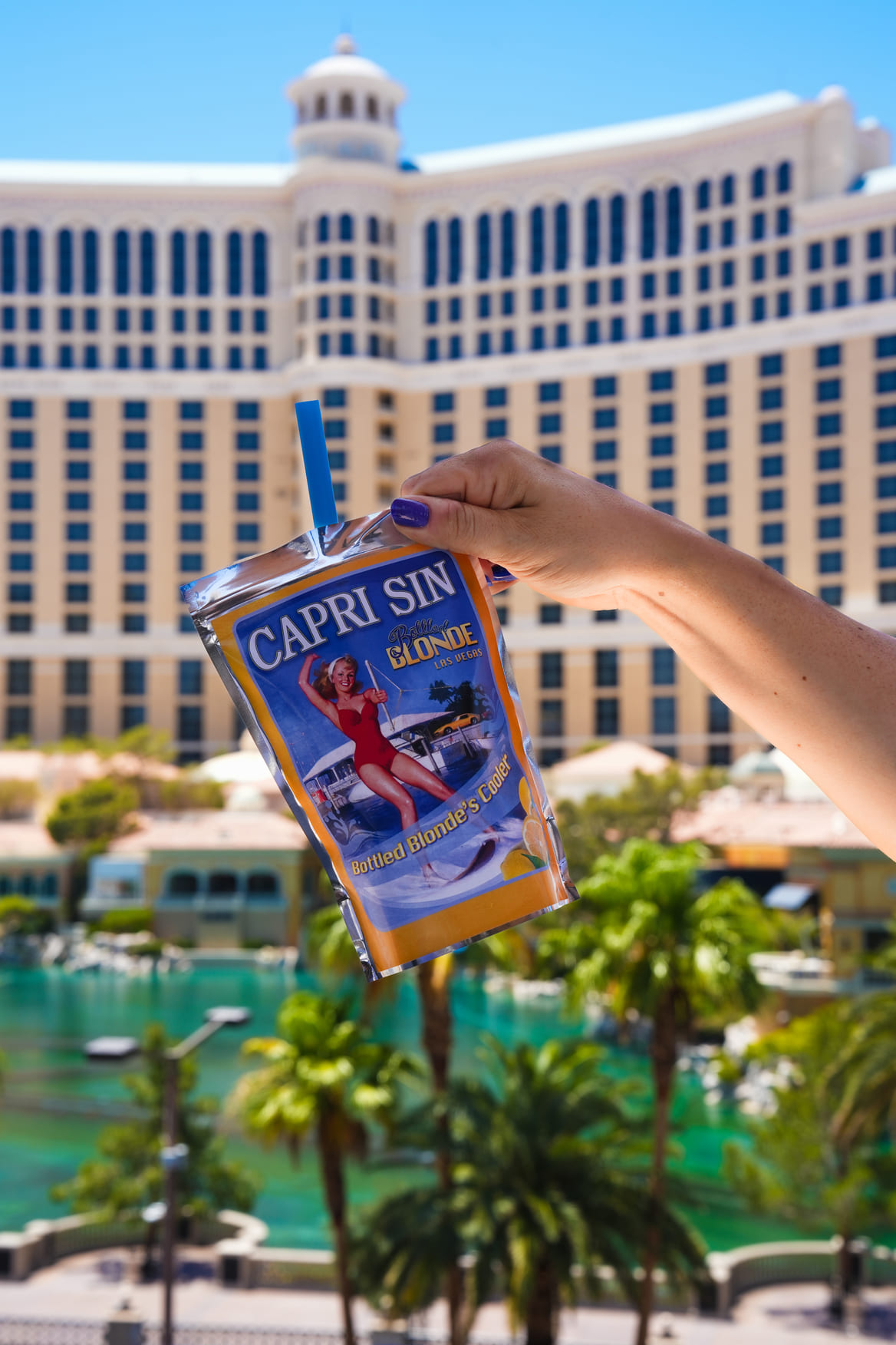 Hand holding a Capri-style drink pouch in front of the Bellagio hotel in Las Vegas