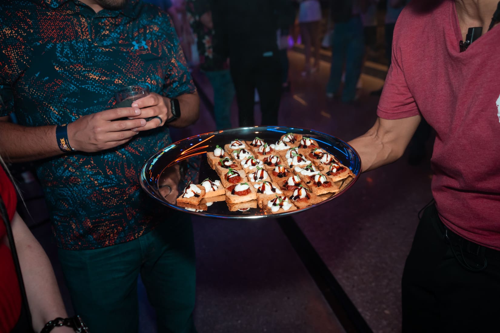 Tray of small appetizer bites being served at a party.