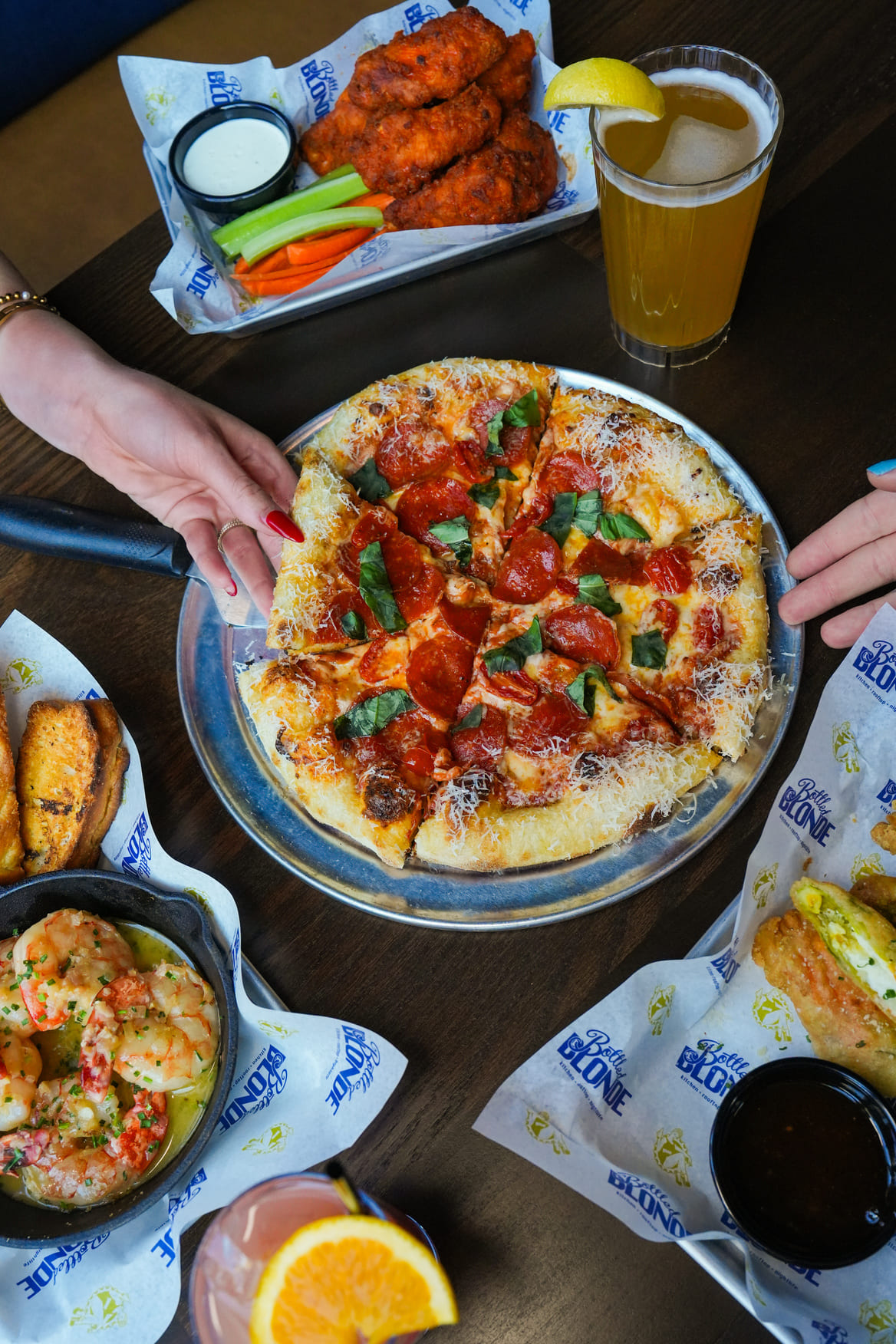 Pizza with pepperoni and basil served with buffalo wings, shrimp, and drinks
