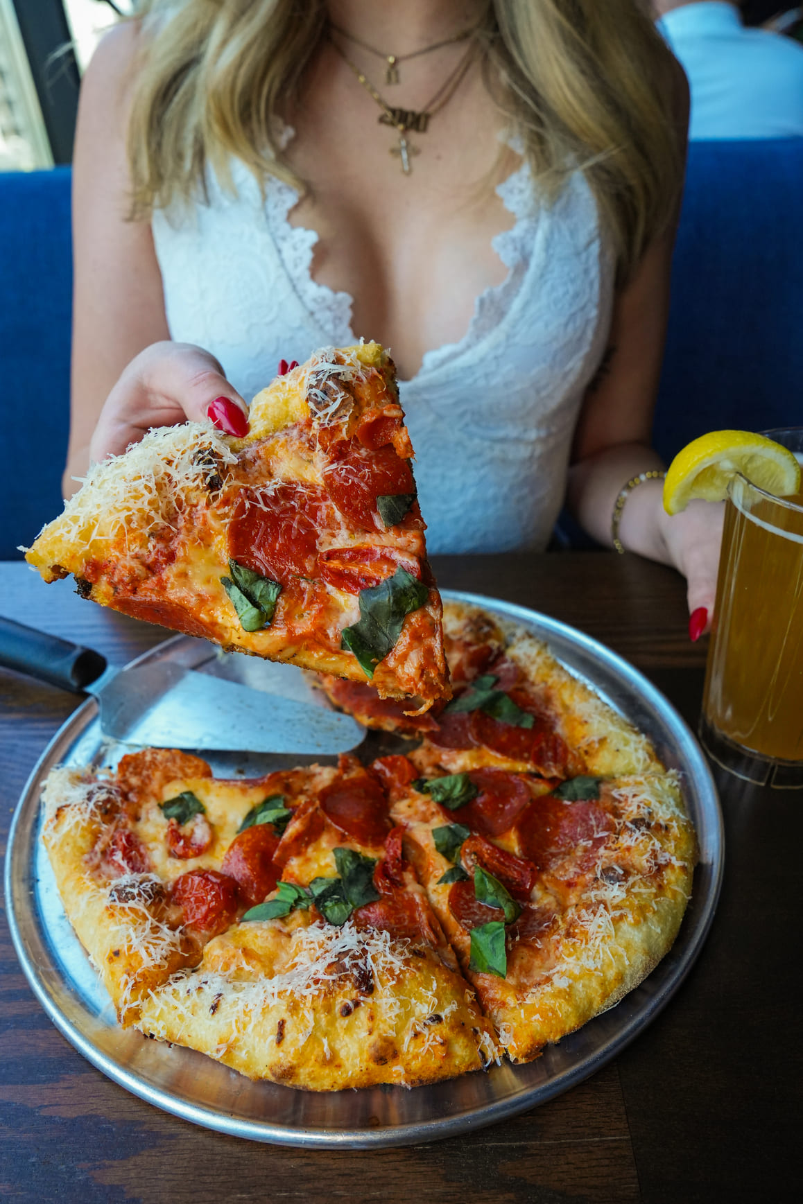Woman holding a slice of pepperoni pizza with basil and grated cheese