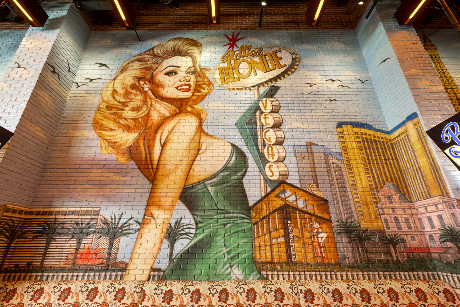 Large wall mural of a blonde pin-up with the words "Bottled Blonde Vegas" and city skyline.
