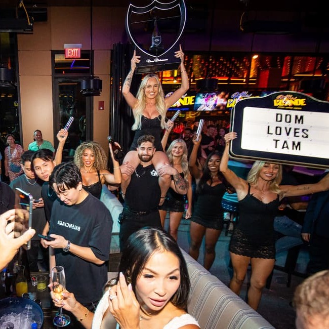 Large bottle service presentation with staff and crowd cheering in nightclub