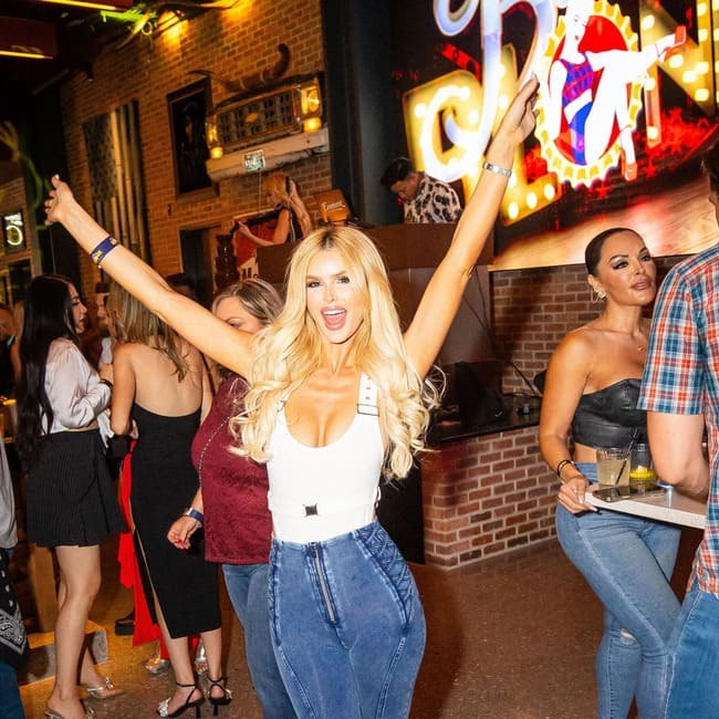 Woman dancing with arms raised on a crowded nightclub dance floor