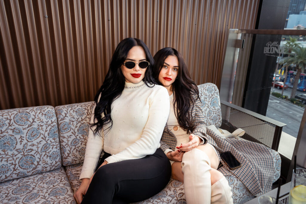 Two people seated together on a cushioned lounge couch in an outdoor patio or terrace setting