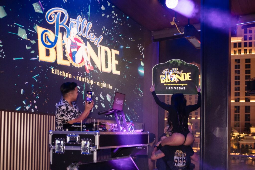 DJ performing at a nightlife venue with guests holding a sign at Blonde Las Vegas