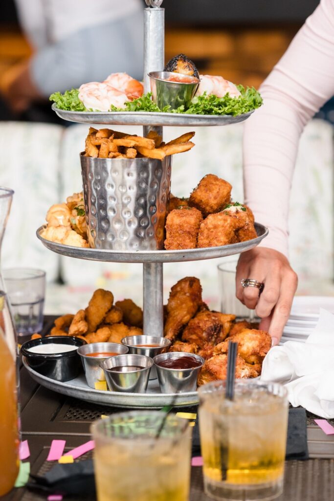 Tiered platter with shrimp, fries, fried appetizers, and dipping sauces on a table